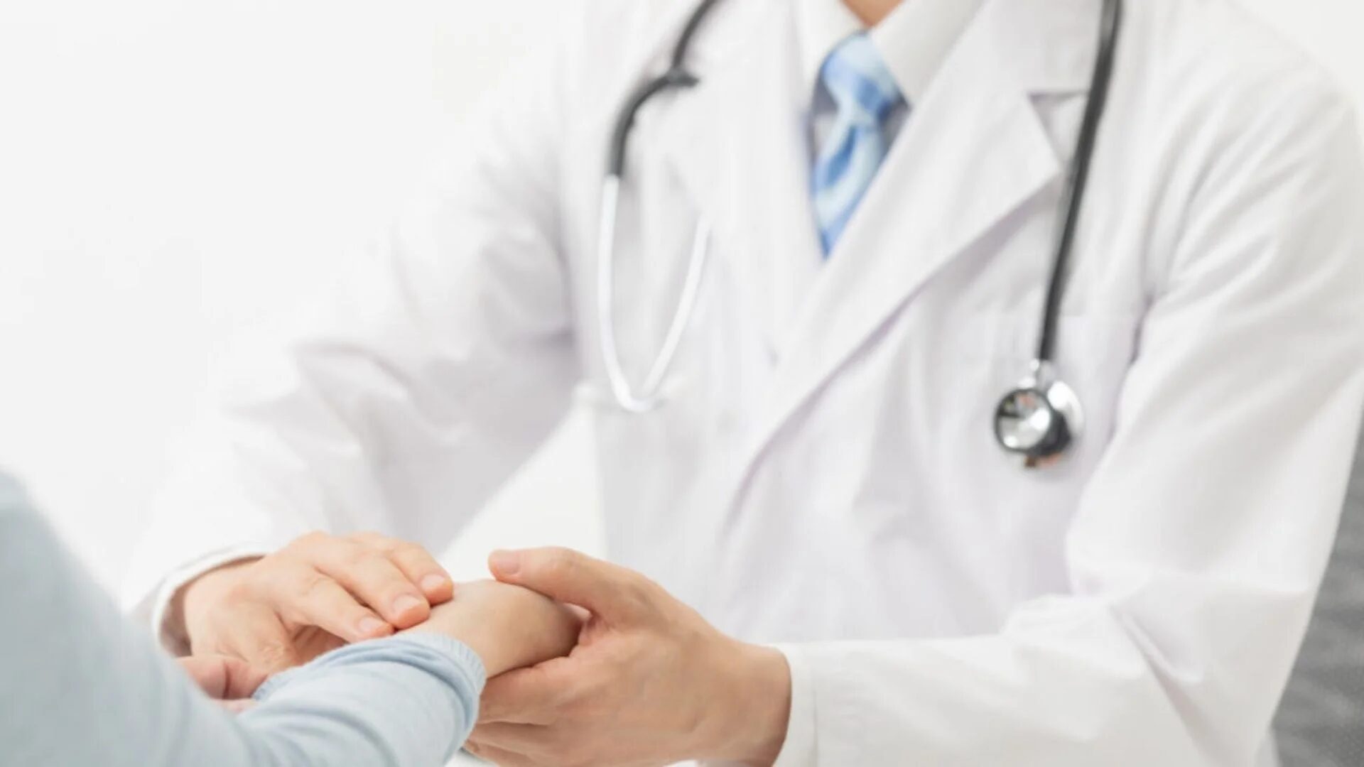 医師が患者の手を優しく握っている様子