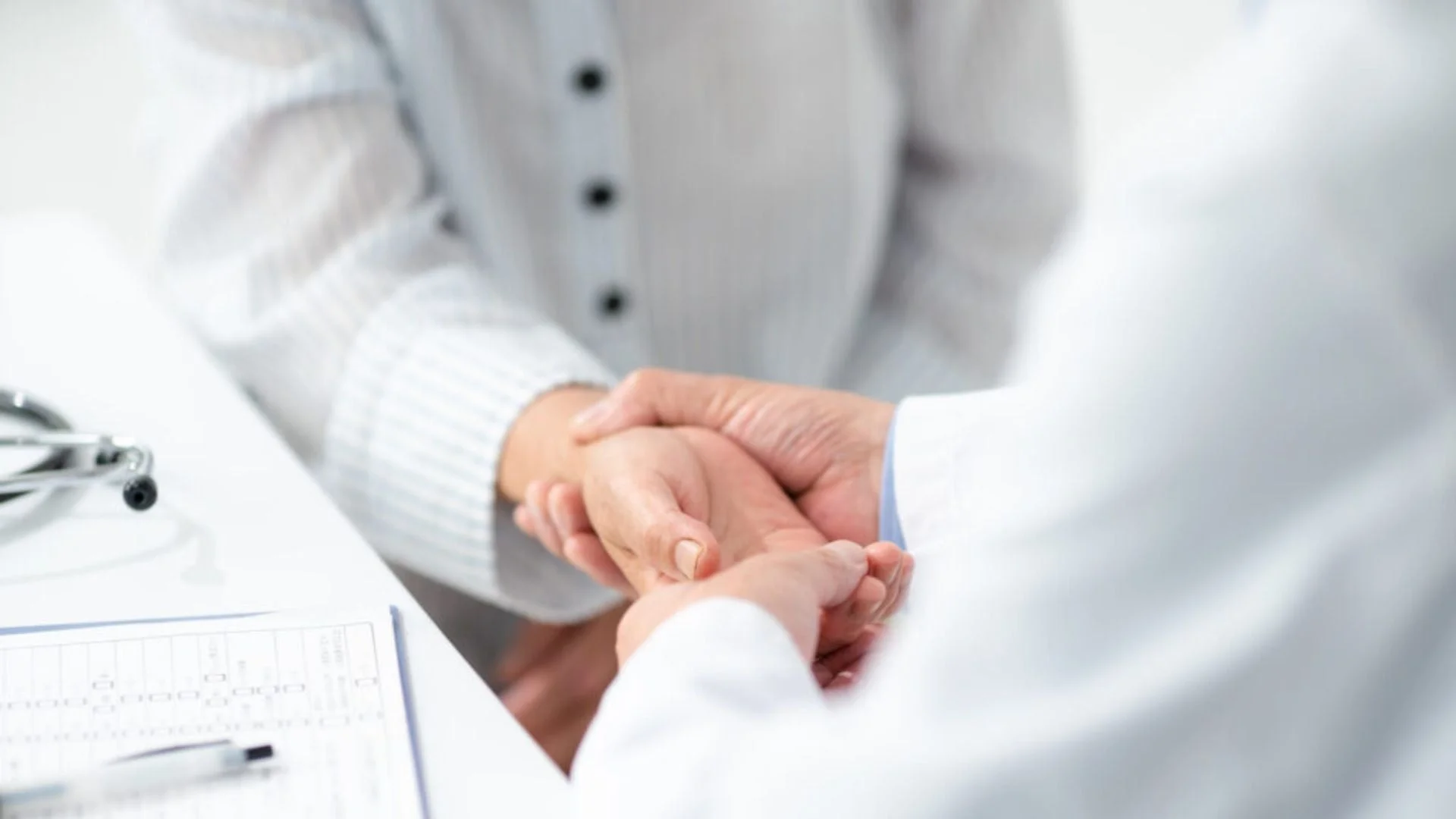 医師が患者の手を優しく握る様子