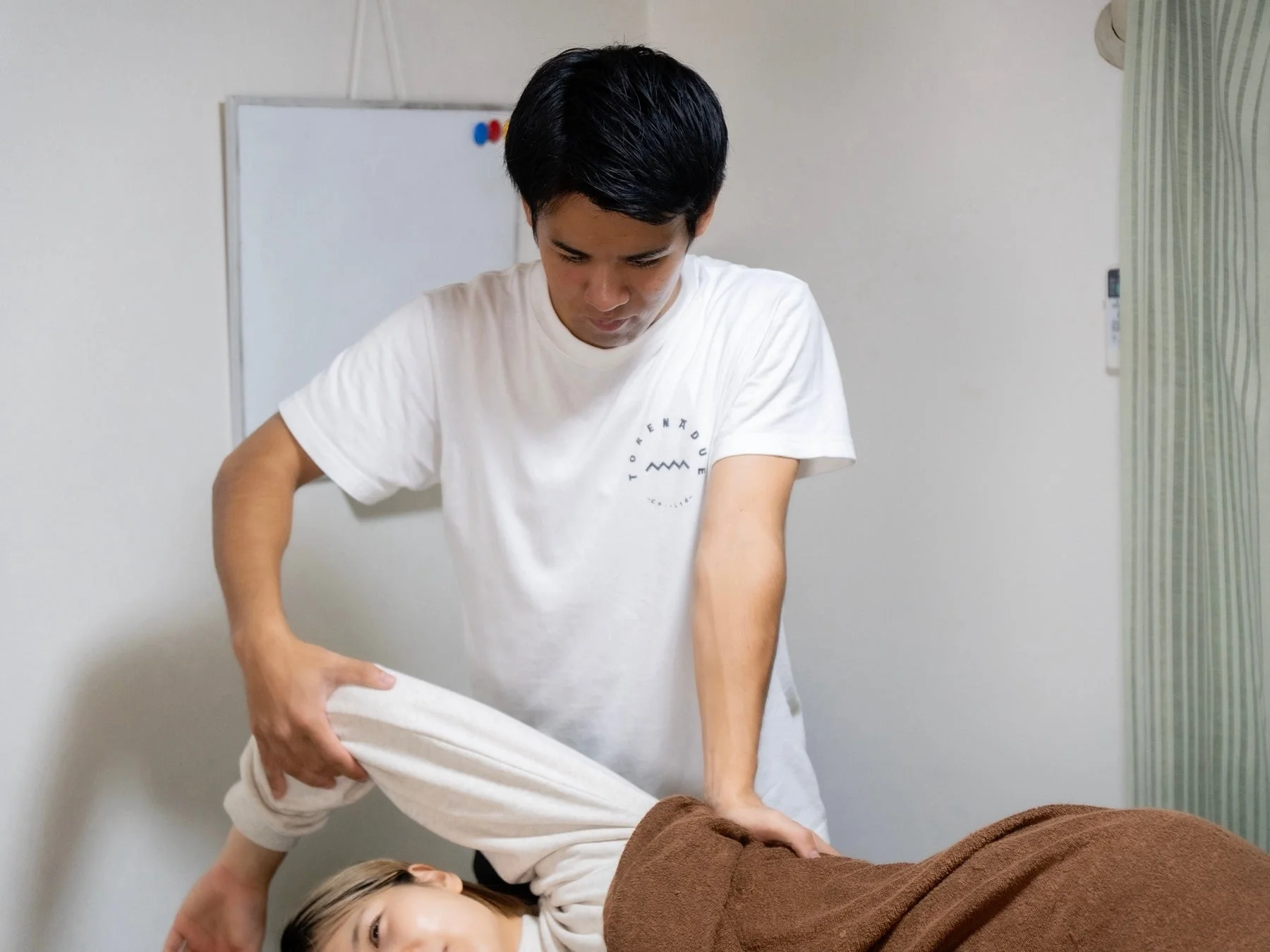 男性がうつ伏せになった女性の脚をストレッチしている様子