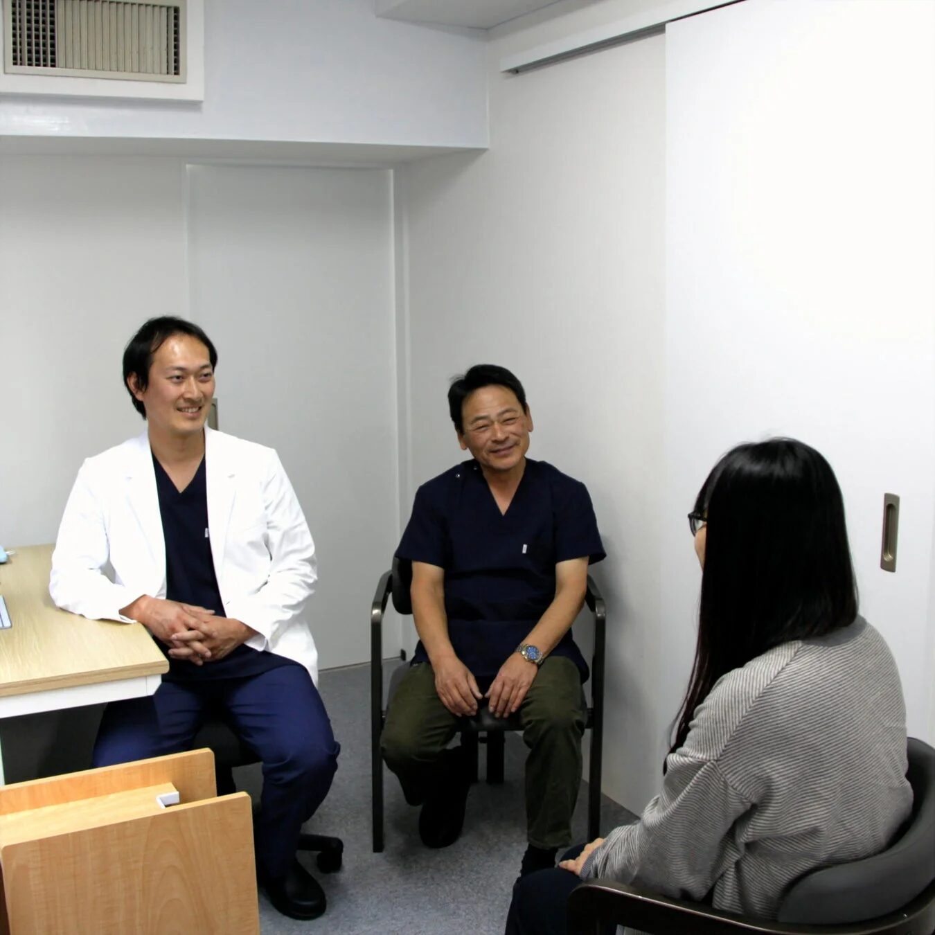 診察室で笑顔で会話する医療従事者と患者