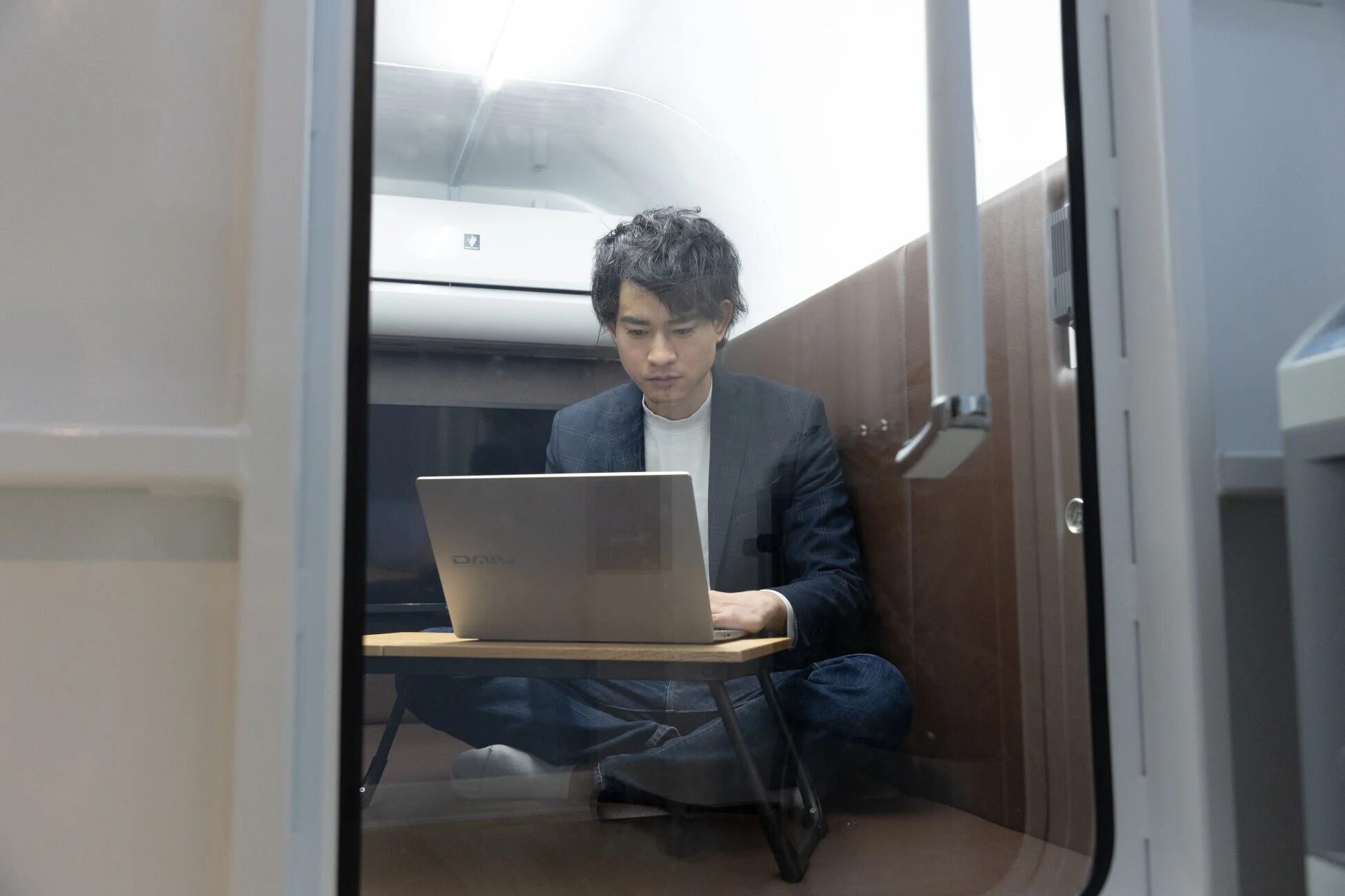 男性が個室のような空間でノートパソコンを使って仕事をしている様子。