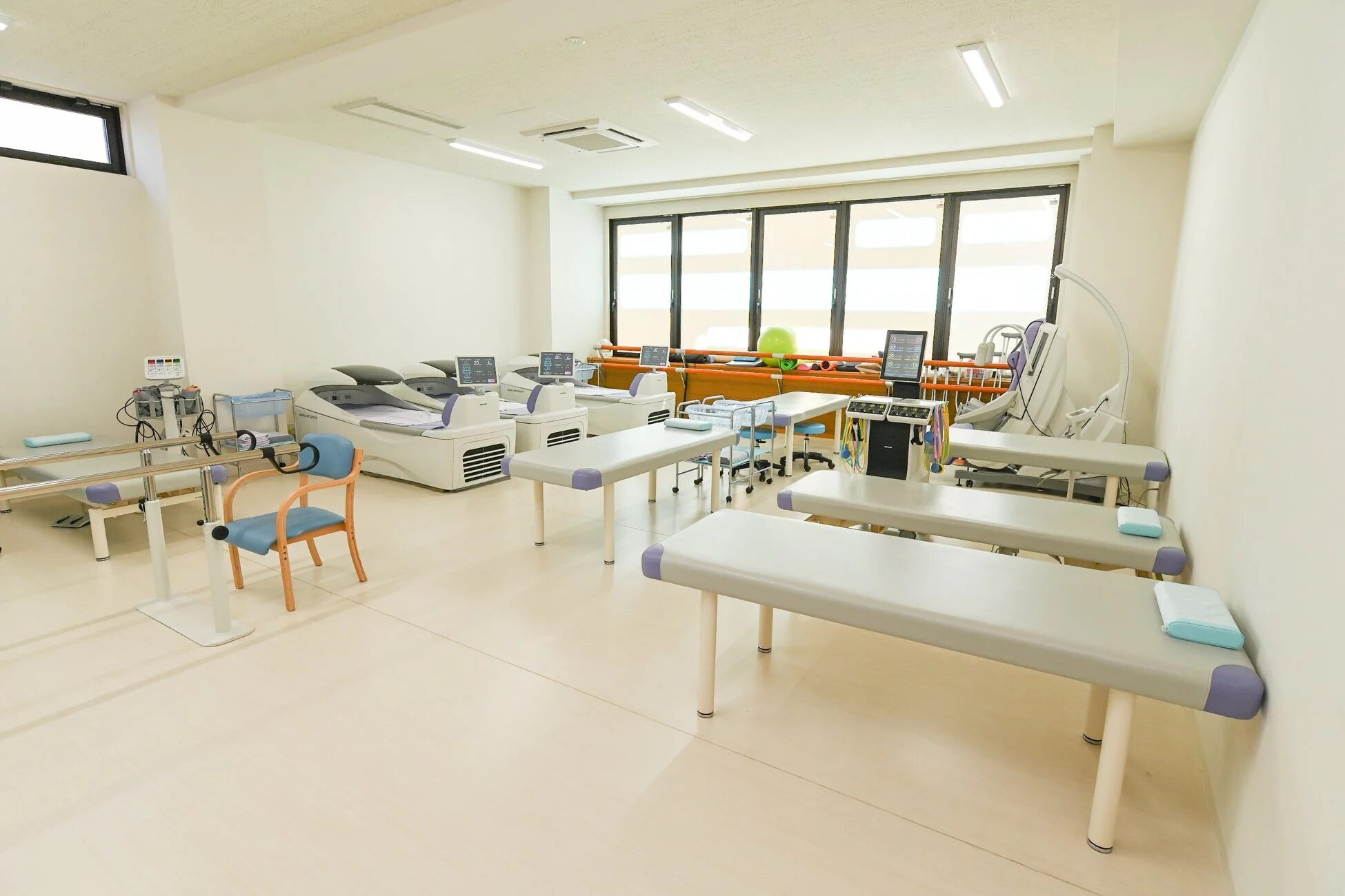 複数のリハビリ用ベッドと医療機器が整然と配置された治療室