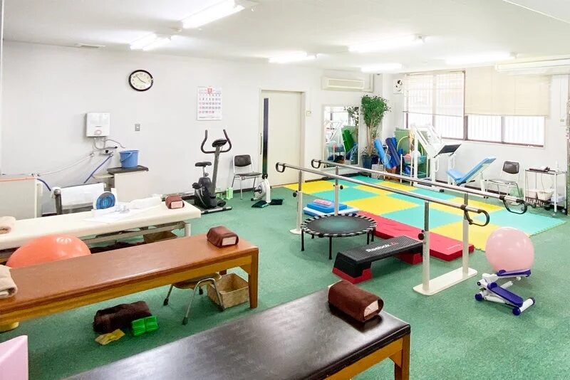 様々な運動器具や治療台が設置された、広々としたリハビリテーションルームの様子です。
