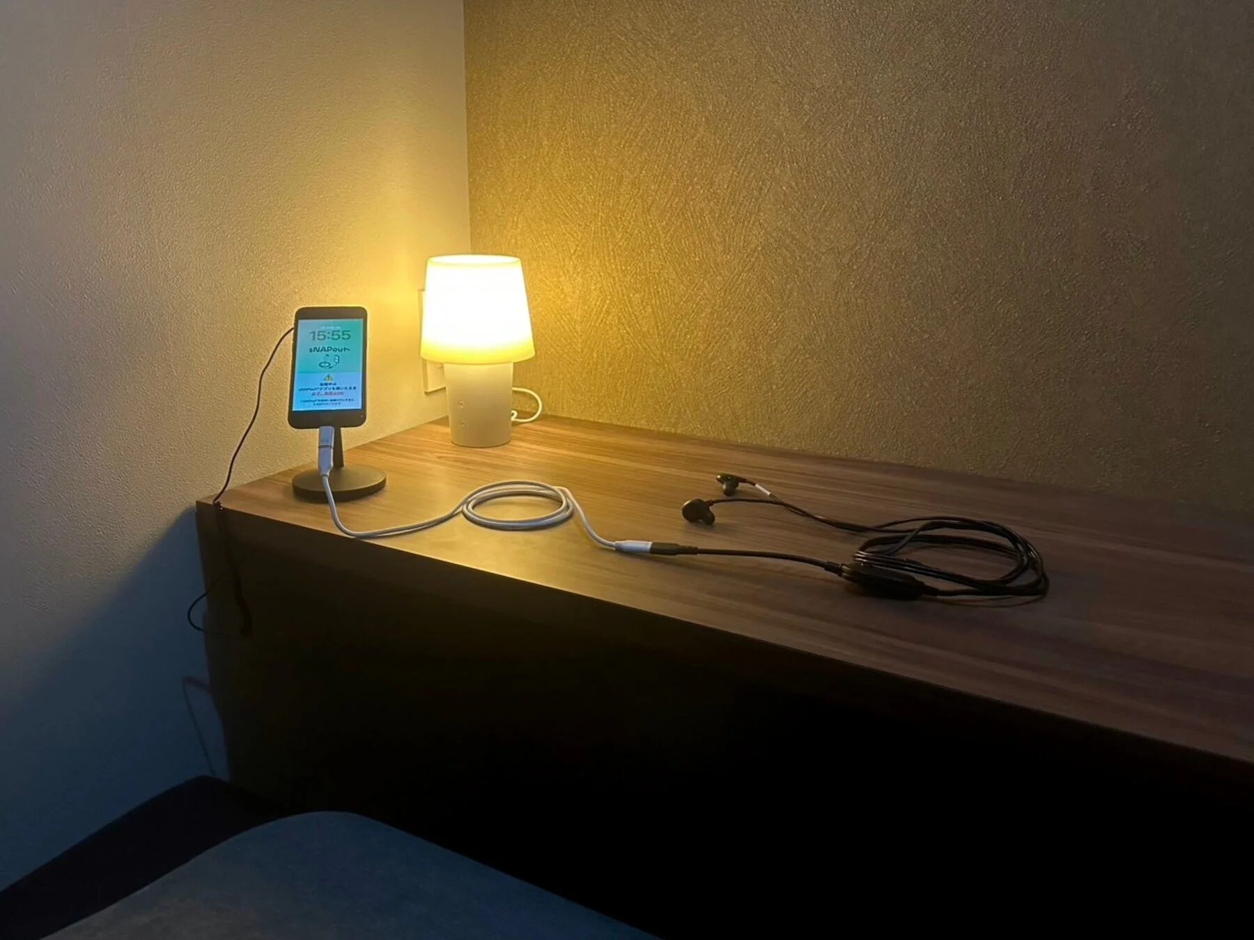 スマートフォン充電中、デスクライトとイヤホン