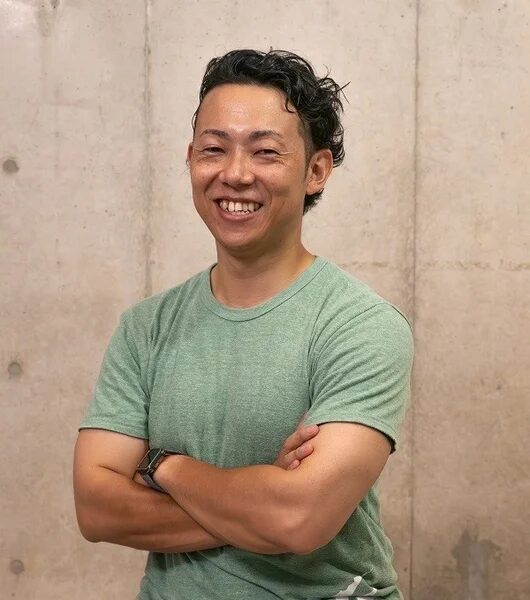 緑色のTシャツを着て腕組みをする男性