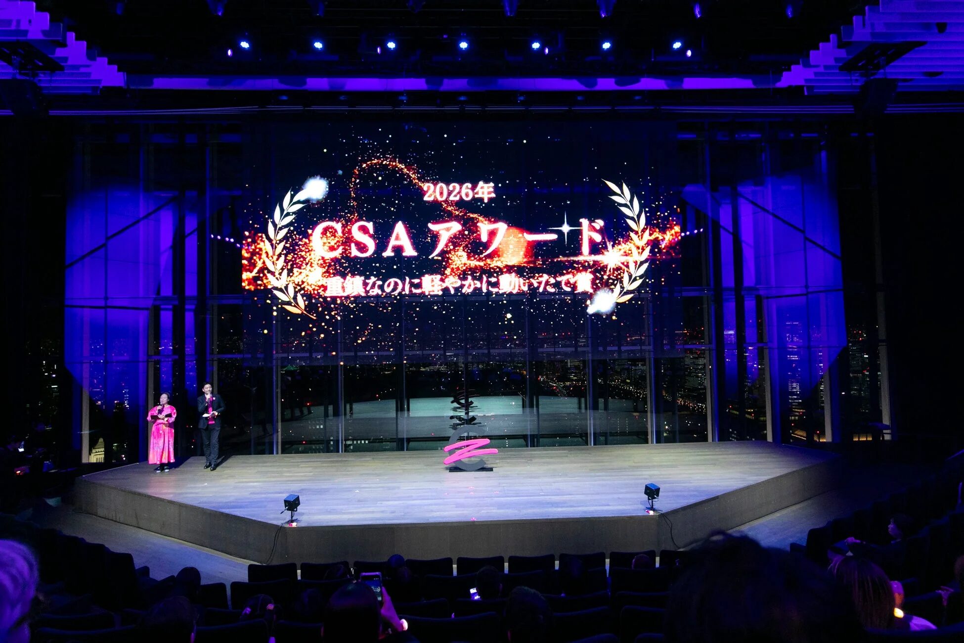 高層ビルからの夜景を背景に、ステージで「2026年 CSAアワード」と表示された大画面が印象的なイベントの様子。