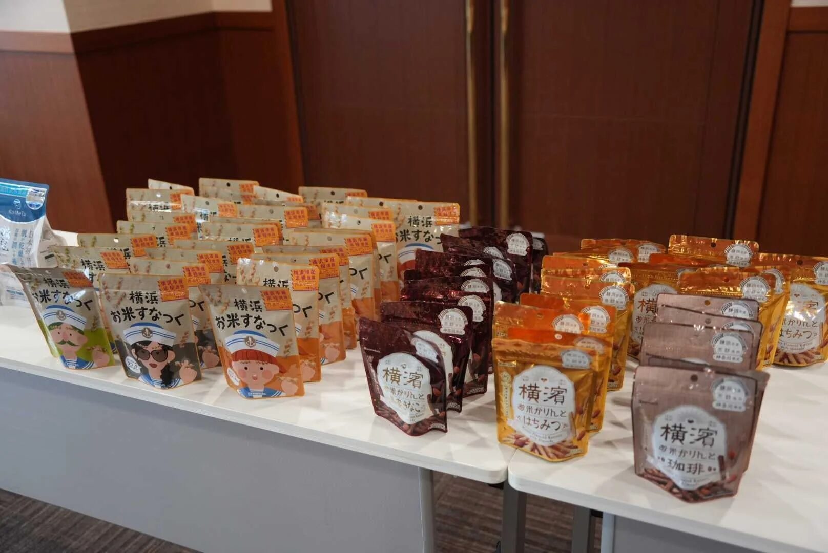 白いテーブルに「横浜お米すなっく」と「横浜菊お米かりんとう」が多数陳列されています。