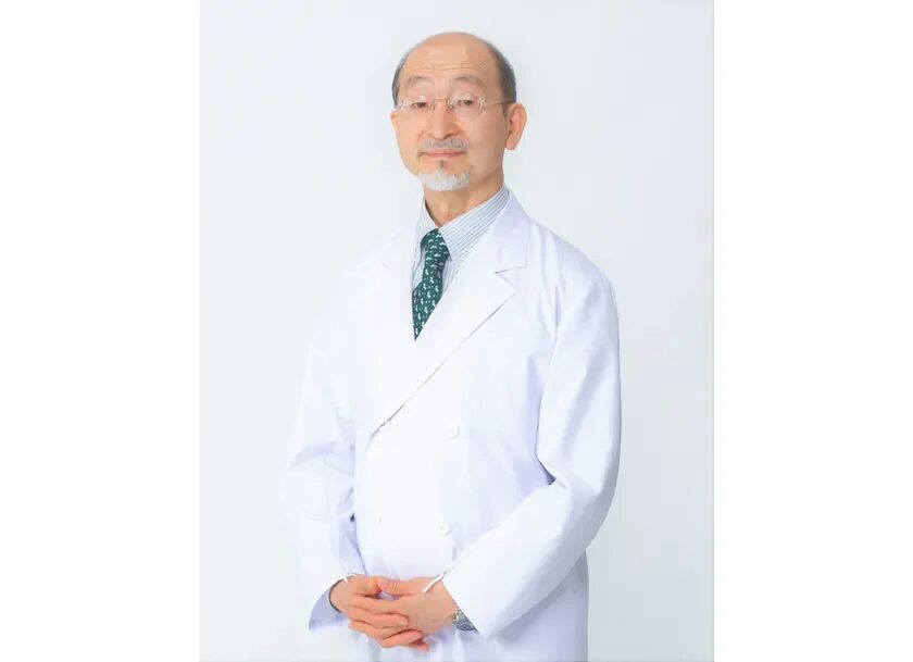 白衣を着用し、眼鏡と髭を蓄えたシニア男性医師のポートレート。手を組んで正面を見つめており、専門性と信頼感のある印象を与えます。