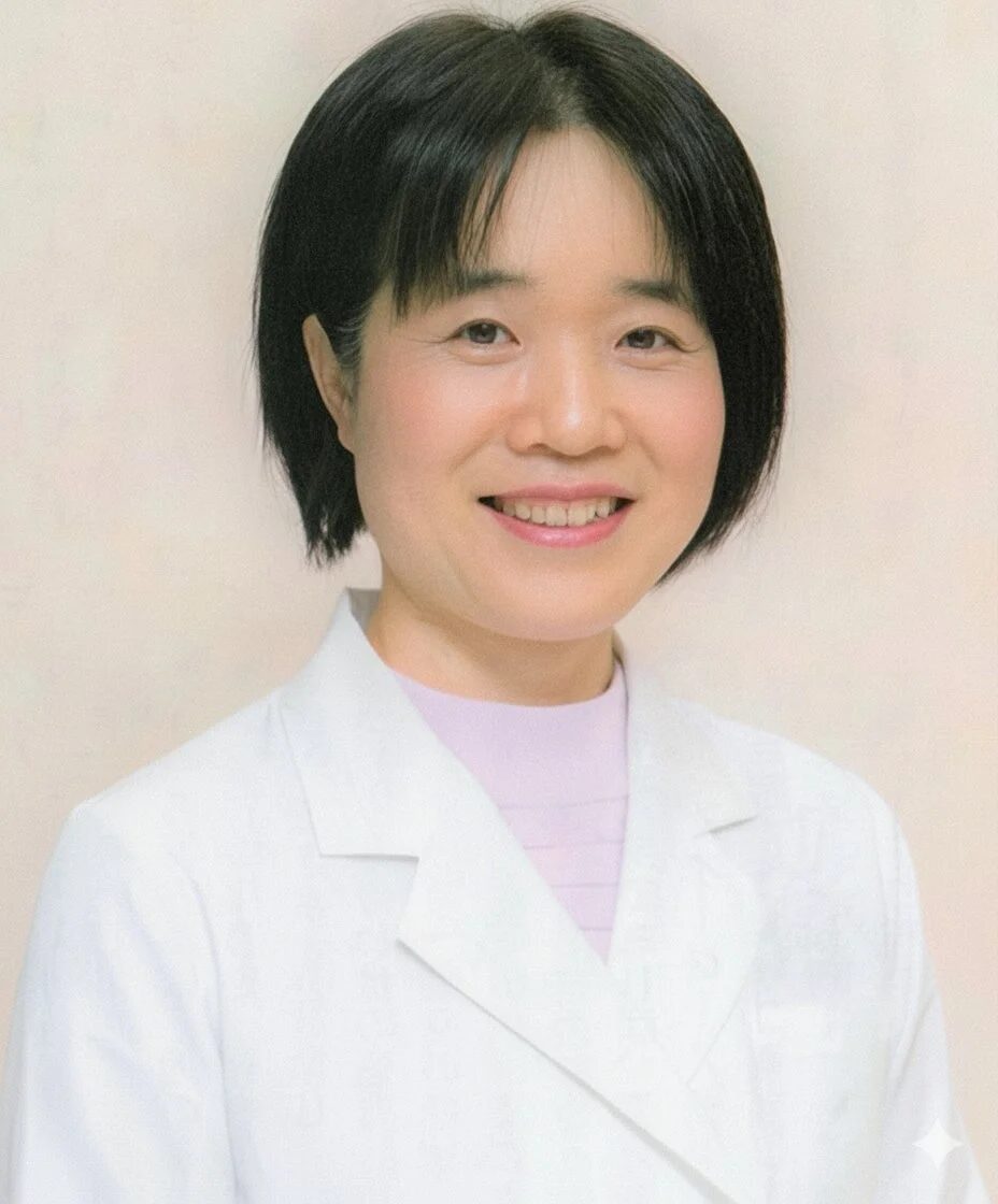 白衣を着用したアジア人女性が、短髪で笑顔を見せているポートレート。