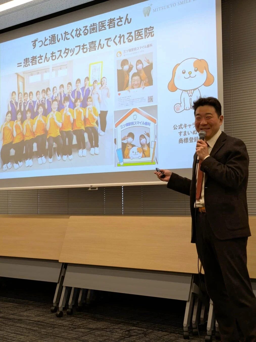 プレゼンテーションのスライドとスタッフ集合写真