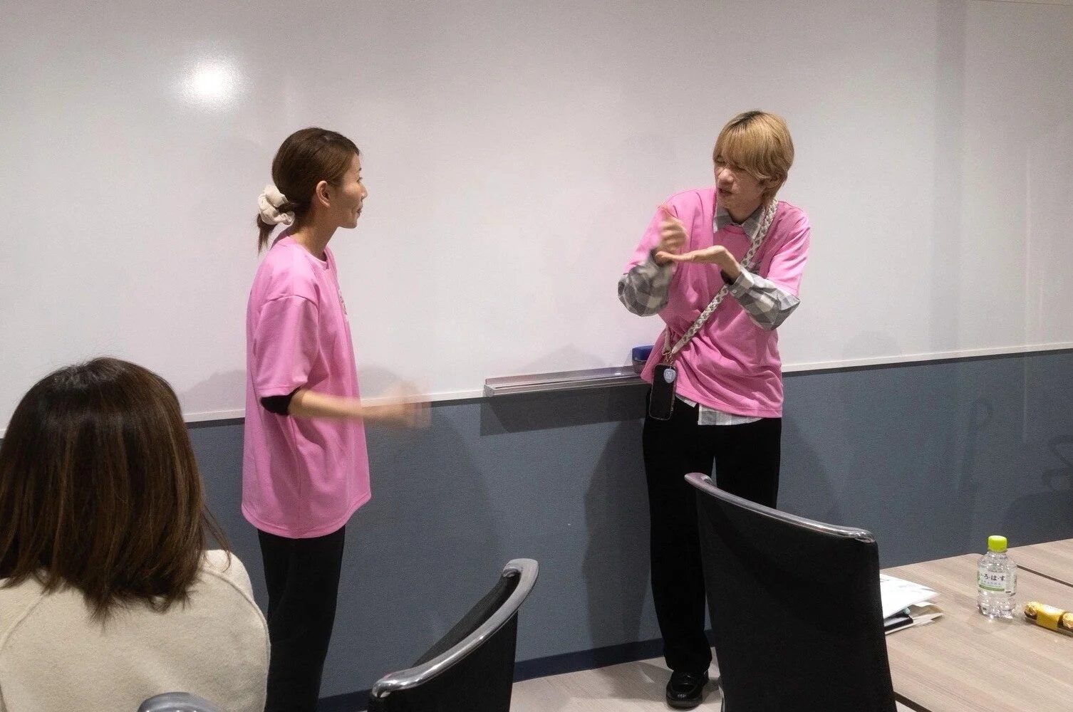 会議室で手話のような動きを交えて話す2人の女性