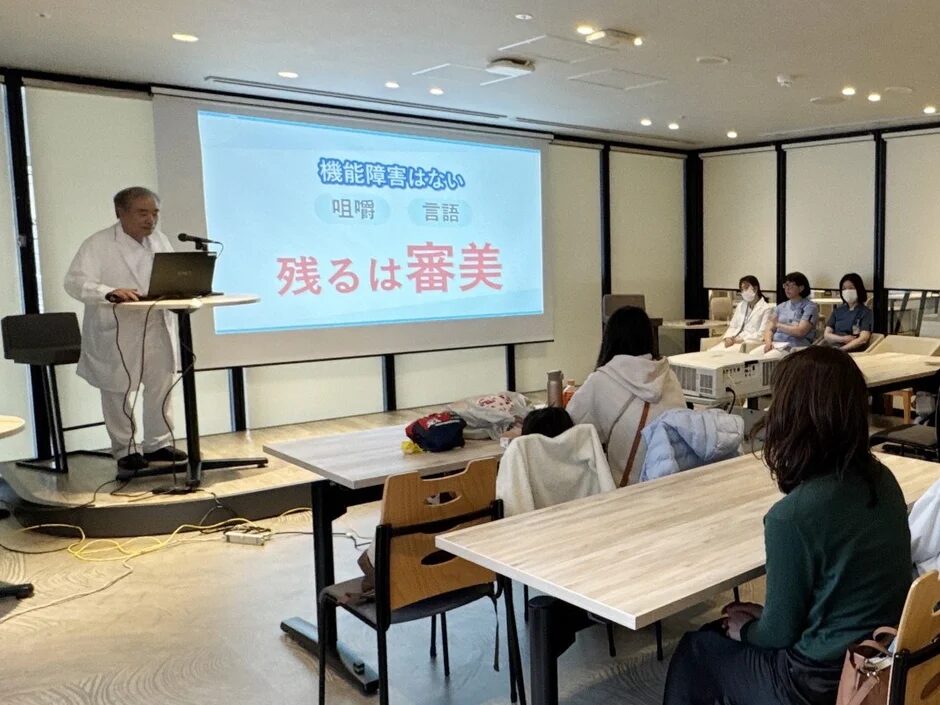 白衣の講師がプレゼンテーションしている様子