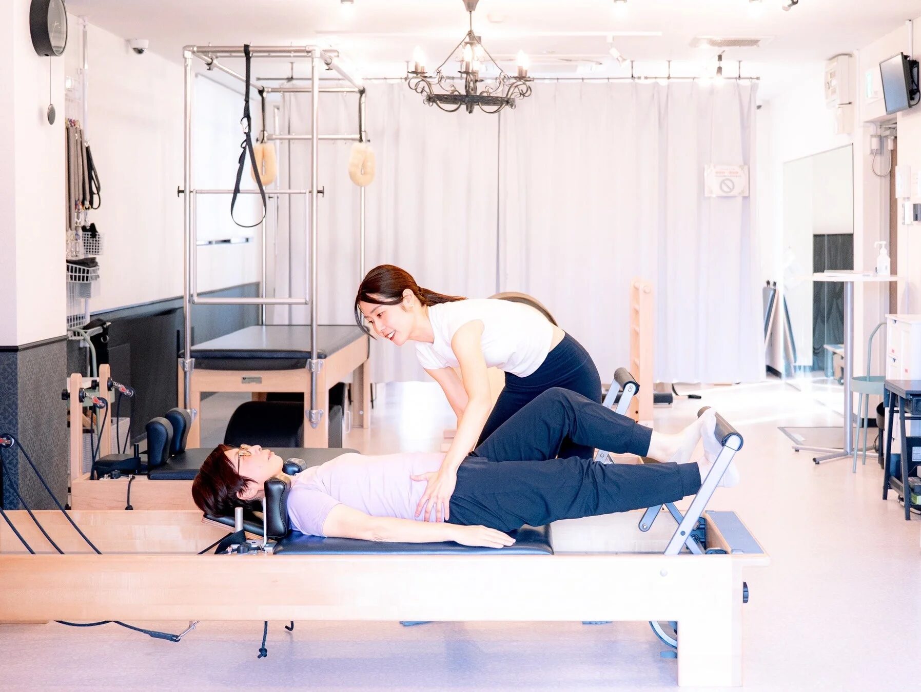 ピラティスインストラクターがリフォーマーマシンを使ってクライアントを指導