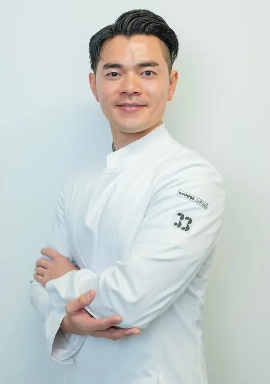 白いユニフォームを着用し、腕を組んで笑顔で立つ道下将太郎医師