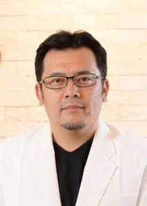 眼鏡をかけ、白いジャケットを羽織ったアジア人男性のポートレート