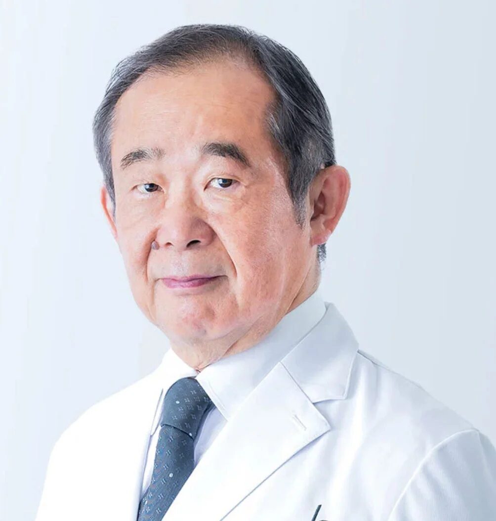 白衣を着たシニアの日本人男性がカメラを見つめているポートレート写真。医療関係者や専門家を思わせる真面目な表情です。