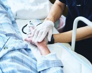 医療従事者が患者の手を優しく握る様子