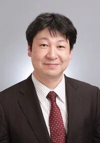 ダークスーツにストライプシャツと赤い水玉模様のネクタイを着用したアジア系の中年男性の肖像写真