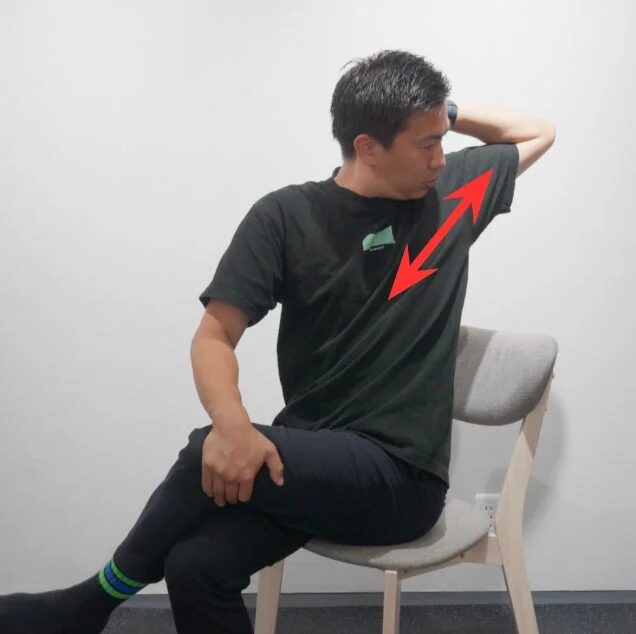 男性が椅子に座って胸から肩にかけてストレッチをしている画像