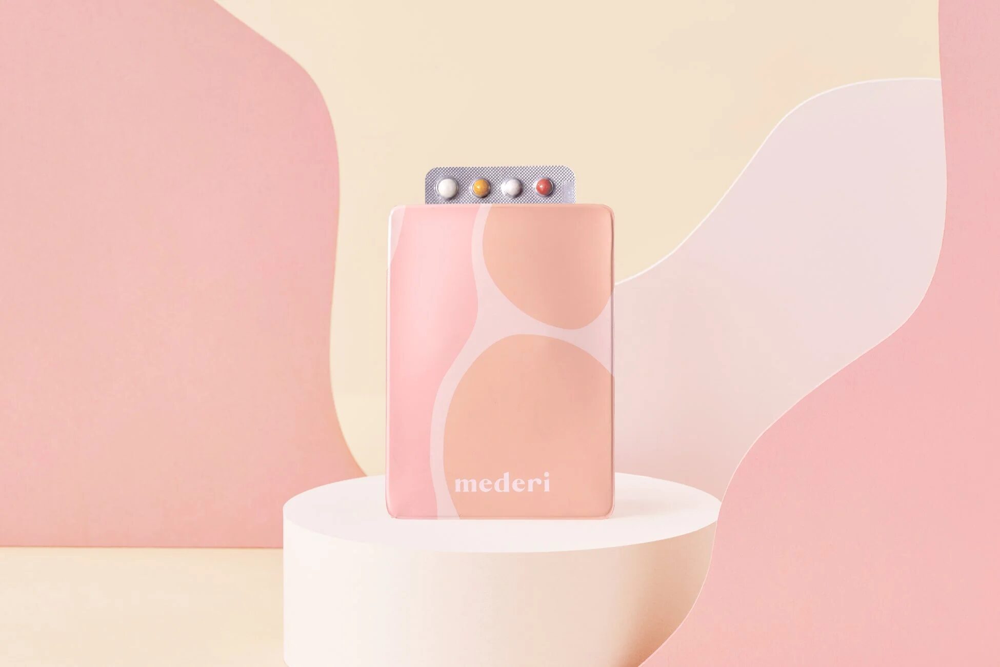 ピンク色のパッケージに入ったピルが白い円柱状の台座に置かれています。