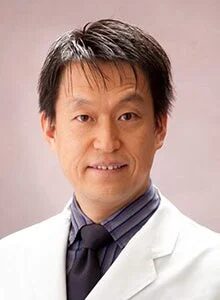 白衣を着用した東アジア系の男性がカメラに向かって微笑んでいるポートレート写真