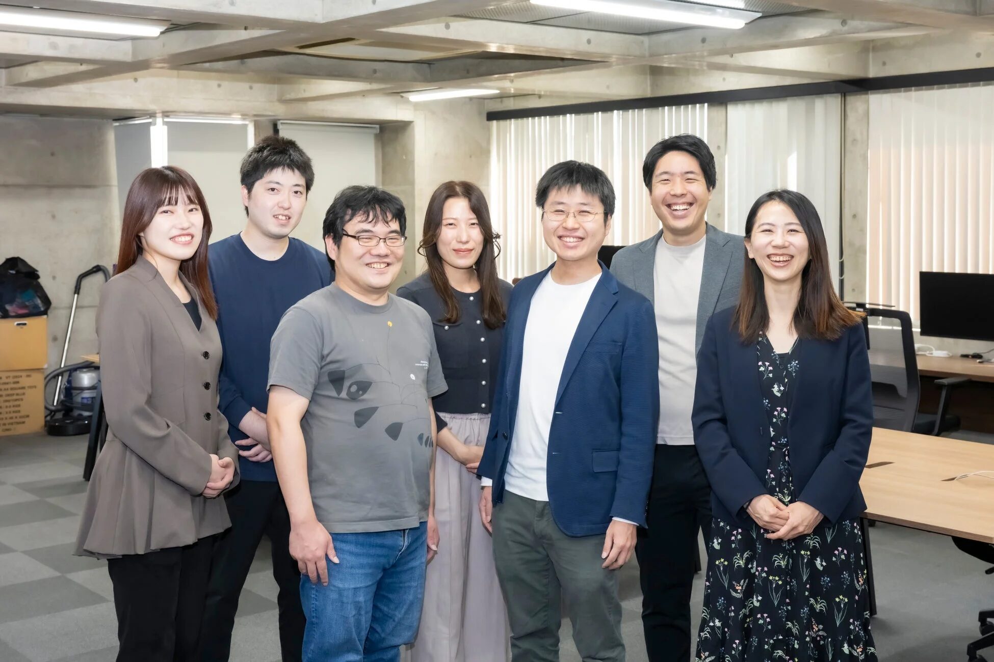 現代的なオフィスで笑顔で並ぶ7人のビジネスパーソン